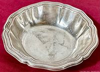 Front angle showing scalloped edge and reflective silver surface with patina and fine scratches