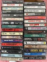 Stack of rock and roll cassette tapes with artists like Led Zeppelin, Rush, Fats Domino, Rod Stewart, Billy Joel, Wilson Phillips, AC/DC, Lionel Richie.
