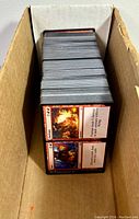 Top view of stacked Magic the Gathering cards showing card fronts with red borders and fantasy artwork visible.
