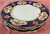 Stack of six Royal Albert Imari plates showing cobalt blue border with floral and gold details.