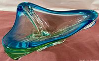 Side angle view showing the sculptural curved edges and color gradients in the blue and green glass bowl.