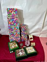 Full view of all Christmas ornaments, wooden Santa, metal Santa key, and colorful nesting gift boxes on a red cloth background