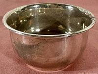 Side angle showing the plain round bowl with tarnish and surface scratches on the exterior silver surface.