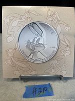 Front view of 2015 Bugs Bunny silver coin against a card with multiple Bugs Bunny sketches.