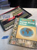Photo showing two vintage stamp albums, one with a red race car on the cover, the other a Learn Explorer World-Wide Postage Stamp Album.