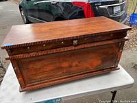Front and side view of the wooden blanket box showing brass studs and side handle.