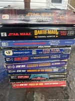 Photo showing the spines of 12 Star Wars and Star Trek pocket books stacked vertically.
