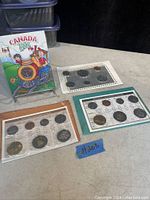 Image showing three uncirculated Canadian coin sets from 1987, 2003, and 2004 sealed in plastic holders with all coins visible and labeled.