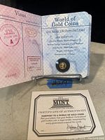 Coin in protective capsule mounted in open World of Gold Coins booklet showing visa-stamp graphics on left and printed specifications on right