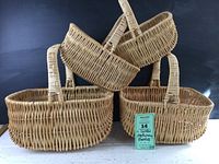Four nested wicker gathering baskets arranged with largest on bottom to smallest on top with a small green note card in front.