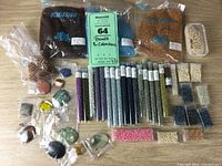 Full lot showing large bags of Toho beads, small containers of seed beads, and stone and glass cabochons scattered on table