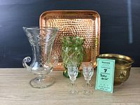 Overall collection showing all items including clear and green vases, copper tray, brass cachepot, and cordial glasses.