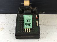 Front view showing the keyboard with numbered keys and label indicating 'Burroughs Adding Machine'.