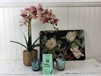 Photo showing entire lot with flower placemats, silk orchid, and three votive candle holders on a white wood background.