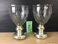 Two etched glass hurricane candleholders with faux mercury glass bases, shown front view on black background with identification card.