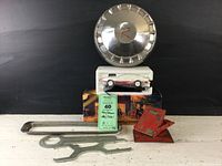 Overview photo showing entire collection with hubcap mounted on black backdrop, chocks, wrenches, Corvette telephone handset with box, and Matchbox fire engine toy