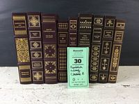 Full view of nine Franklin Library classic books with beautiful bindings in warm colors with gold imprint showing titles and authors.