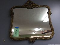 Full view of the rococo gilt framed mirror showing ornate top center crest and decorative bottom detail
