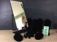 Black velvet jewelry display stands set against a black backdrop with a tall rectangular vanity mirror showing overall items included in the lot