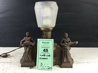 Front view showing entire lamp with seated musicians and frosted glass shade, including cord with plug.