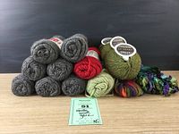 Photo showing lots of 14 skeins of yarn in gray, red, green, pale green, and multicolor.
