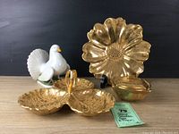 Photo of all four items in the lot: tri-sectioned gold relish dish, flower plate on stand, small square bowl, and white ceramic pigeon figurine.