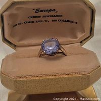 Open presentation box showing the cornflower blue sapphire ring and interior lid imprint.