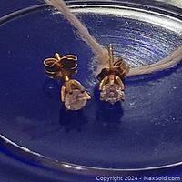 Front view of both stud earrings on blue surface