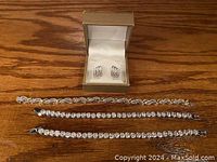 Photo showing three bracelets and one pair of earrings in a box, placed on wood surface.