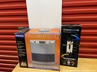 Both boxed items side by side on fabric surface and orange background