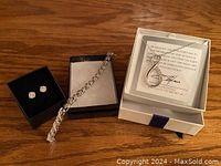 Full view of all jewellery pieces in their boxes showing necklace, earrings, and bracelet detail.