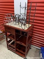 Full view of wood bar cart with marble top and four metal wine racks on top.