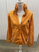 Front view of mustard yellow Bench jacket on mannequin showing zipper closure, collar, and pockets.