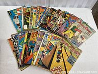 Lot of comic books arranged on a white surface showing multiple titles including Superman and Archie with visible wear.