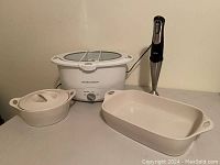Crock Pot slow cooker, hand blender, and two Corelle baking dishes shown together with lids and power cords.