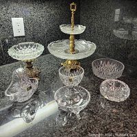 Wide view of collection showing two-tier serving stand, compote, small basket, and assorted bowls on granite countertop.