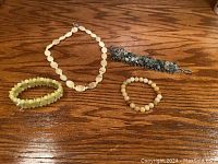 Set of three bracelets and one necklace displayed on wooden surface