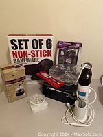 Overview of kitchen essentials including boxed bakeware set, spiral slicer, hand blender, glass serving tray and cookie press