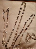 All chains and bracelet displayed on fabric background