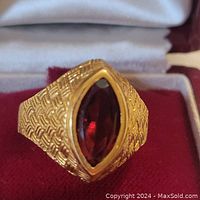 Close-up front view of ring showing marquise garnet gemstone set in textured gold band