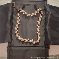 Full view of the MM Crystal necklace laid flat showing the alternating pearls and crystals attached to gold-tone chain with adjustable clasp.