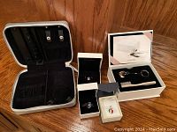 Photo showing Pandora charms in boxes alongside an open black velvet-lined jewelry box and a black zippered jewelry case.