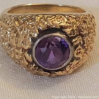 Front view of ring showing textured gold band and bezel set purple amethyst
