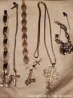 Full view of all jewelry pieces laid on decorative cloth showing variety of bracelets, necklaces, pins, and earrings.