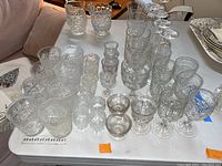 Multiple glassware items including tumblers, stemmed glasses, and small goblets arranged on a table.