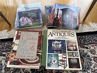 Books arranged in two piles on the floor, including visible titles of cookbooks and the Encyclopedia of Antiques.