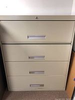Front view of the 4-drawer metal file cabinet showing drawer handles and key lock on top drawer.