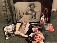 Photo showing the large framed black-and-white Marilyn Monroe photograph along with multiple Marilyn Monroe magazines and prints arranged together