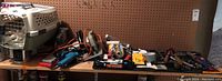 Overview of lot showing tools on a table including power tools, handtools, painting materials, and a pet carrier