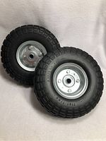 Two flat free tires shown side by side with tread and rims visible.